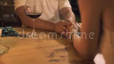 在餐厅的浪漫约会中，幸福的一对夫妇手捧着蜡烛和酒杯在餐桌上。 男子和妇女